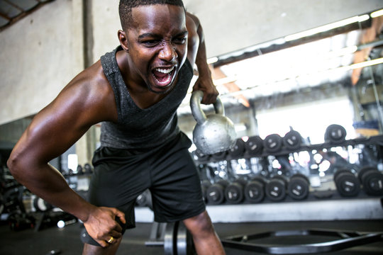 Close up of male athlete bodybuilder active lifting a kettlebell, emotion, intensity, determination
