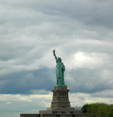 Fototapeta na wymiar Statue of liberty seen from the front with a grey and cloudy sky as background in Manhattan, New York City.
