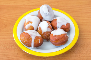 Homemade mini paczki with icing on plate.