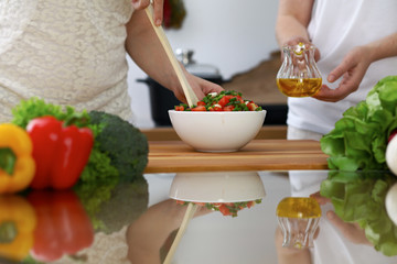 Close-up of  human hands  cooking in a kitchen. Friends having fun while preparing fresh salad....