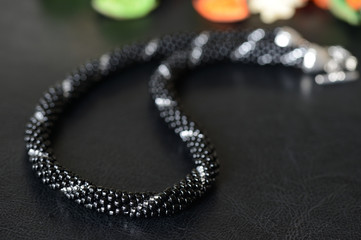 Black beaded necklace with silver line on a dark background