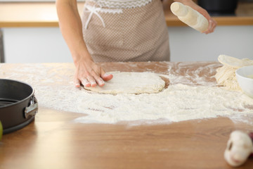 Female hands making dough for pizza or bread while using rolling pin. Baking concept