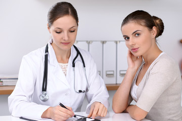 Doctor and  patient  sitting at the desk. The physician or therapist makes a diagnosis. Health care, medicine and patient service concept