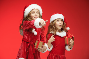 Two happy girls in santa claus hats with gift boxes