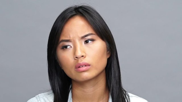 Young displeased asian woman isolated looking camera