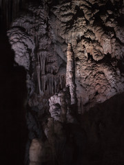 Spéléologie dans une grotte avec stalagmite et drapé en lumière dans une salle de la caverne.