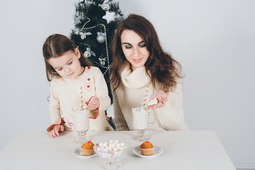 Obraz na płótnie Canvas Mother and little daughter drink cocoa with marshmallows