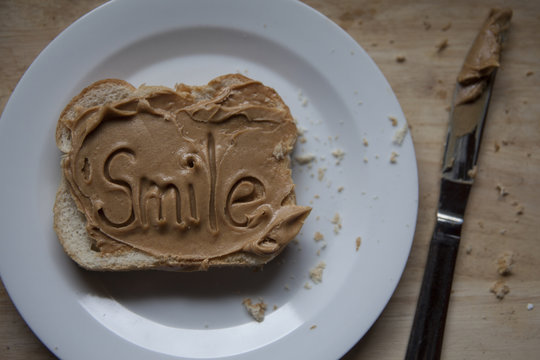 slice of bread smothered in peanut butter with the word smile written in the peanut butter