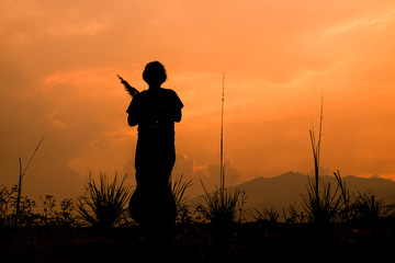Girl standing on the meadow at sunset