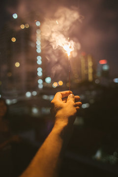 Hand burning and incense stick at night with the city lights in the backgrond