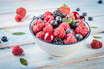 Fresh berries in a bowl on wooden background.