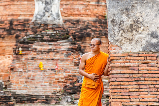 Monk standing and look at view in front of buddha statue at old temple, Ayutthaya Province, Thailand