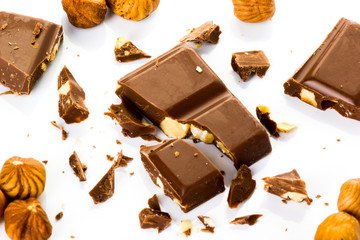 Piece of chocolate with hazelnuts set in several on a white background