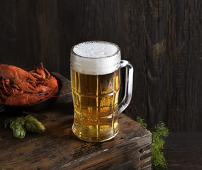 Glass of beer and a boiled crayfishes in a plate on a wooden background