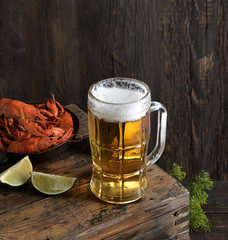 Glass of beer and a boiled crayfishes in a plate on a wooden background