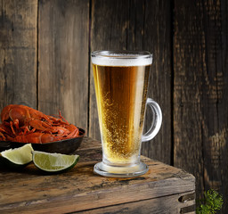 Glass of beer and a boiled crayfishes in a plate on a wooden background