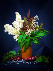 bouquet of summer flowers with Rowan leaves in a brown vase