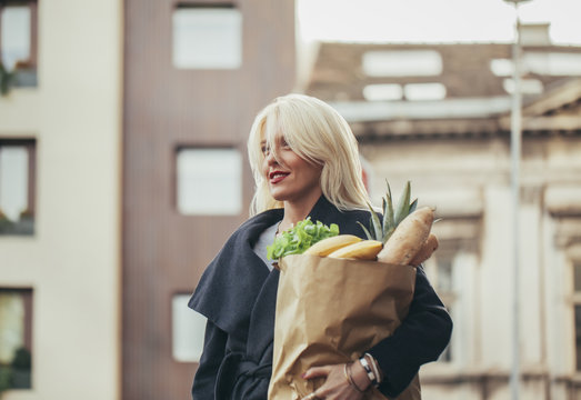 Beautiful Blonde Woman Carrying a Bag With Groceries