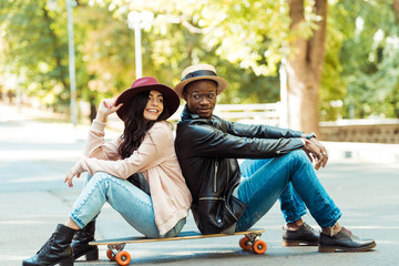 couple in hats sitting on longboard