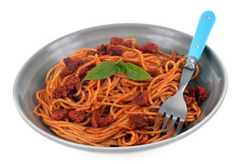 Assiette de spaghetti à la sauce tomate et au chorizo avec des feuilles de basilic sur fond blanc