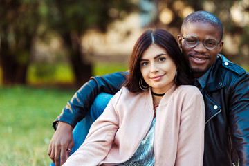 multicultural couple sitting on grass