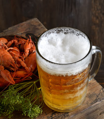 Glass of beer and a boiled crayfishes in a plate on a wooden background