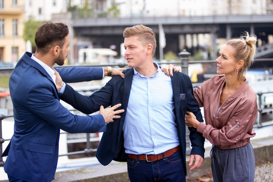 two men fighting while a woman is trying to intervene