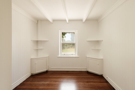empty room with freshly painted white walls and polished timber floors