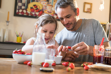 A father and his little girl eating strawberries and sugar