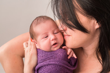 Happy family couple in love on the background. Portrait of happy young family tenderly keeping their sleeping baby on gray background.