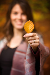 young woman holding a leave towards camera