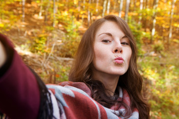 young woman outside in autumn and taking a selfie