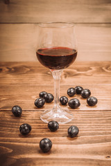 Glass of red wine and grapes on rustic wood table