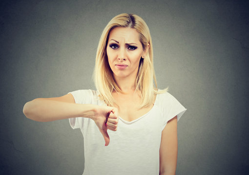 Woman giving thumb down gesture looking with negative expression and disapproval