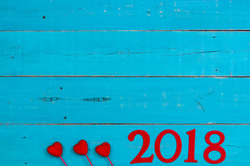 Year 2018 in bold red with hearts border on antique rustic teal blue wood background