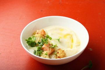Cream soup with fish and croutons in white bowl