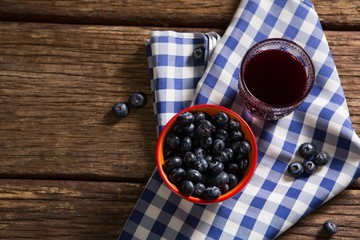 Bowl of blueberries and juice on wooden table