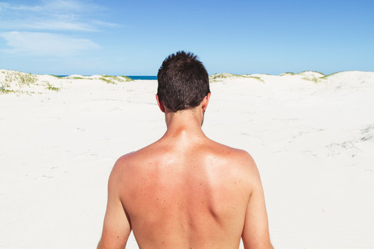 Young man seen from the back on a deserted beach