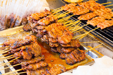 pork on the grill with flame. / Street food in Thailand. / thai style bbq grilled pork./ Grilled pork skewers at night market.
