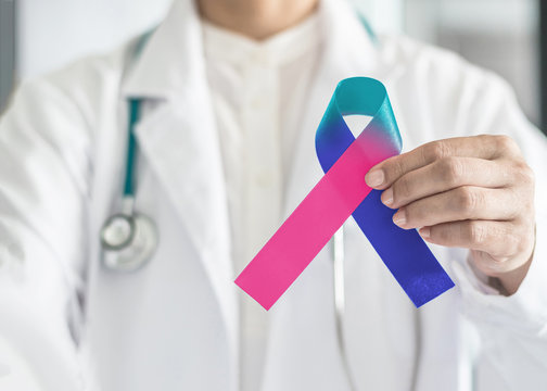 Thyroid cancer awareness ribbon in Teal Pink Blue symbolic bow color in doctor's hand to support patient with tumor illness
