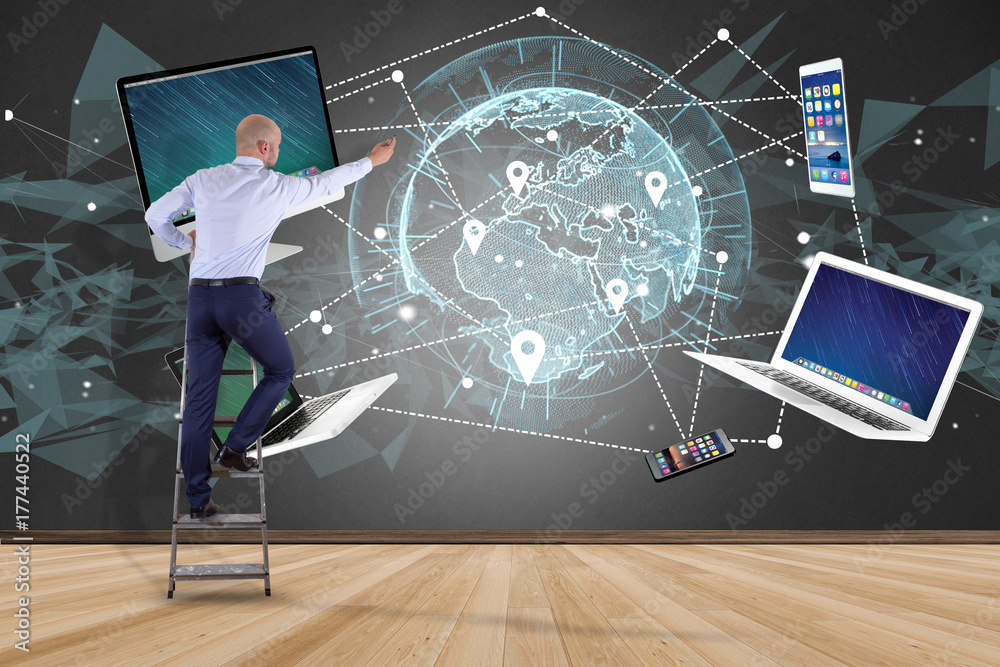 Poster businessman in front of a wall with computer and devices displayed on a futuristic interface with in