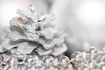 Abstract christmas background with soft focus. Silhouettes of silver colored pine cone and thread with beads and blurred balls.
