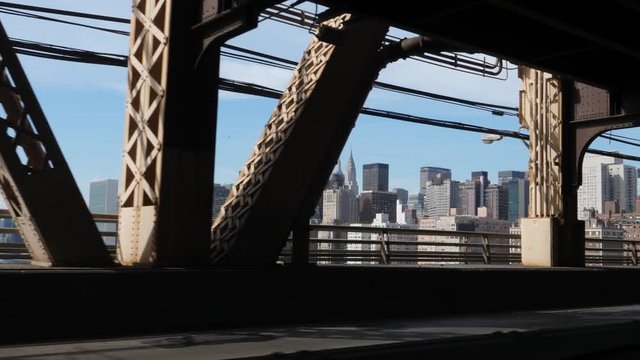 A passenger's perspective driving over the Ed Koch Queensboro Bridge with the Manhattan skyline in the distance.  	