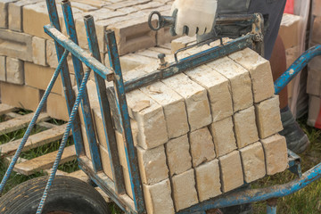 Fototapeta na wymiar Wheelbarrow construction with bricks, Gripping pliers for bricks