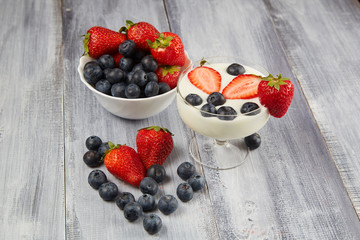 Strawberries, blueberries with yoghurt on a wooden background