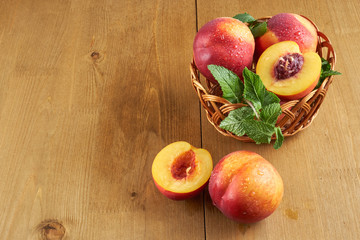 peaches in a wicker basket on wooden table with blurred background