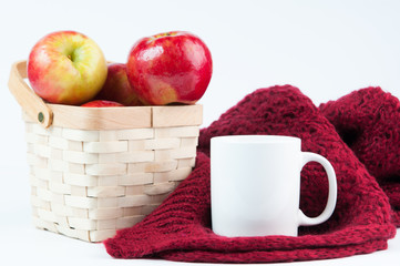 Red apples in a basket with a cozy blanket and mug on a white background