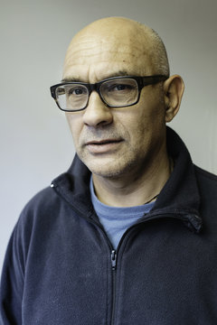 Portrait of a bald man with glasses on.