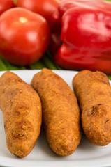 Muchin, an ecuadorian typical food on a white plate with a blurred tomato and pepper