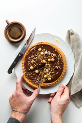 Italian walnut cake crostata with chocolate and hazelnuts. and coffee . men's hands take a cut piece